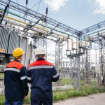 Two specialist electrical substation engineers inspect modern high-voltage equipment. Energy. Industry